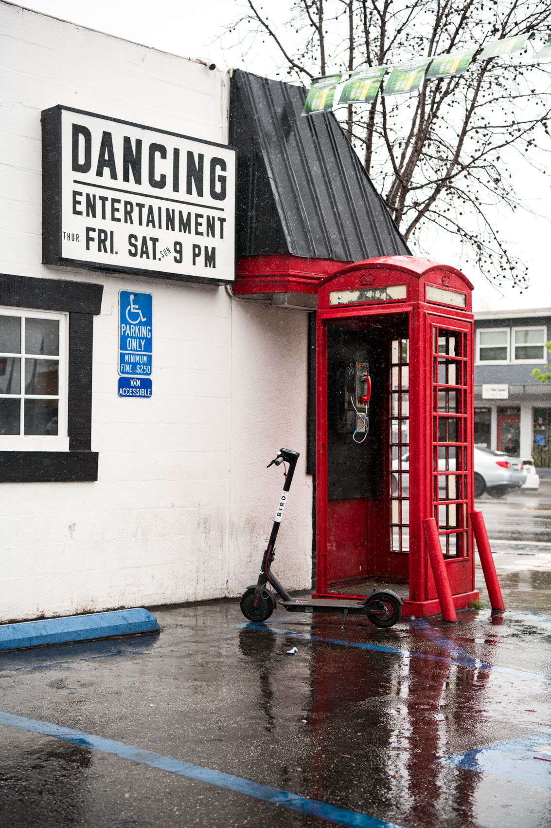 A bird docks scooter in front of a phone booth in the rain in Venice, Calif.