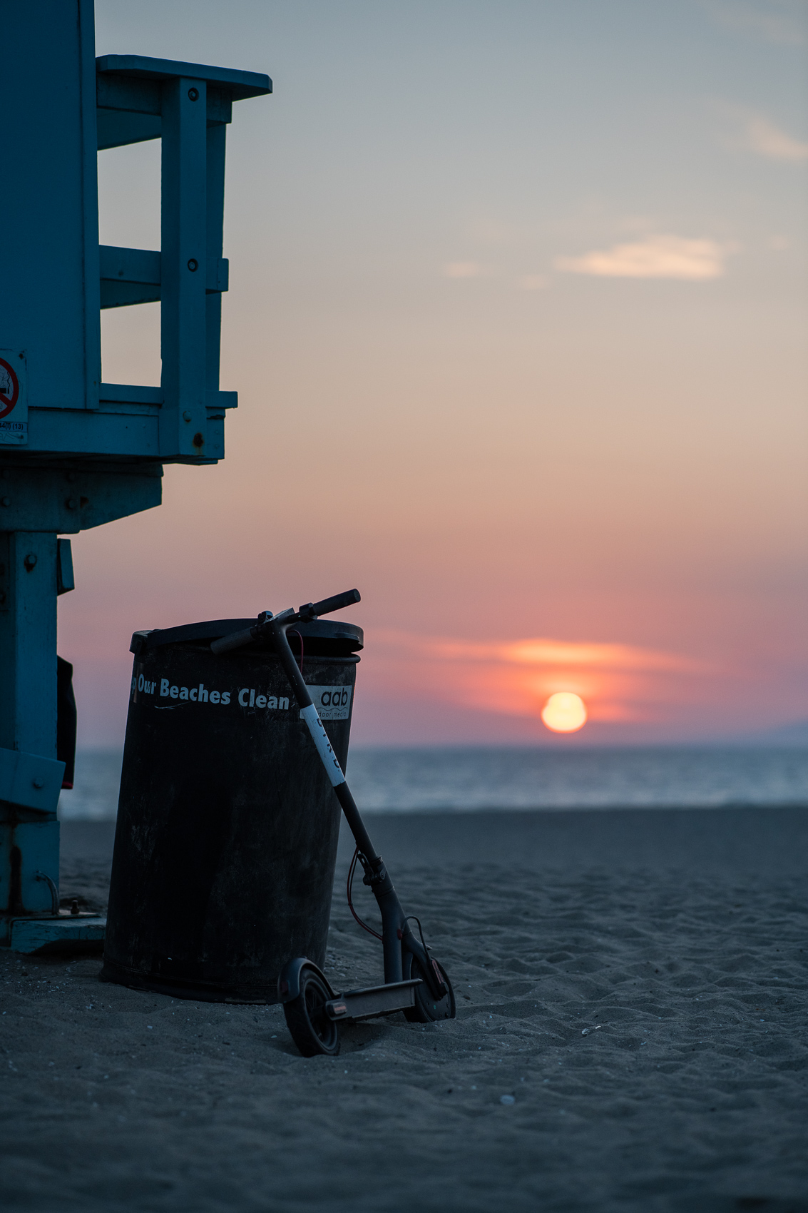 A Bird scooter watches the sunset by a lifeguard stand  in Venice Beach.