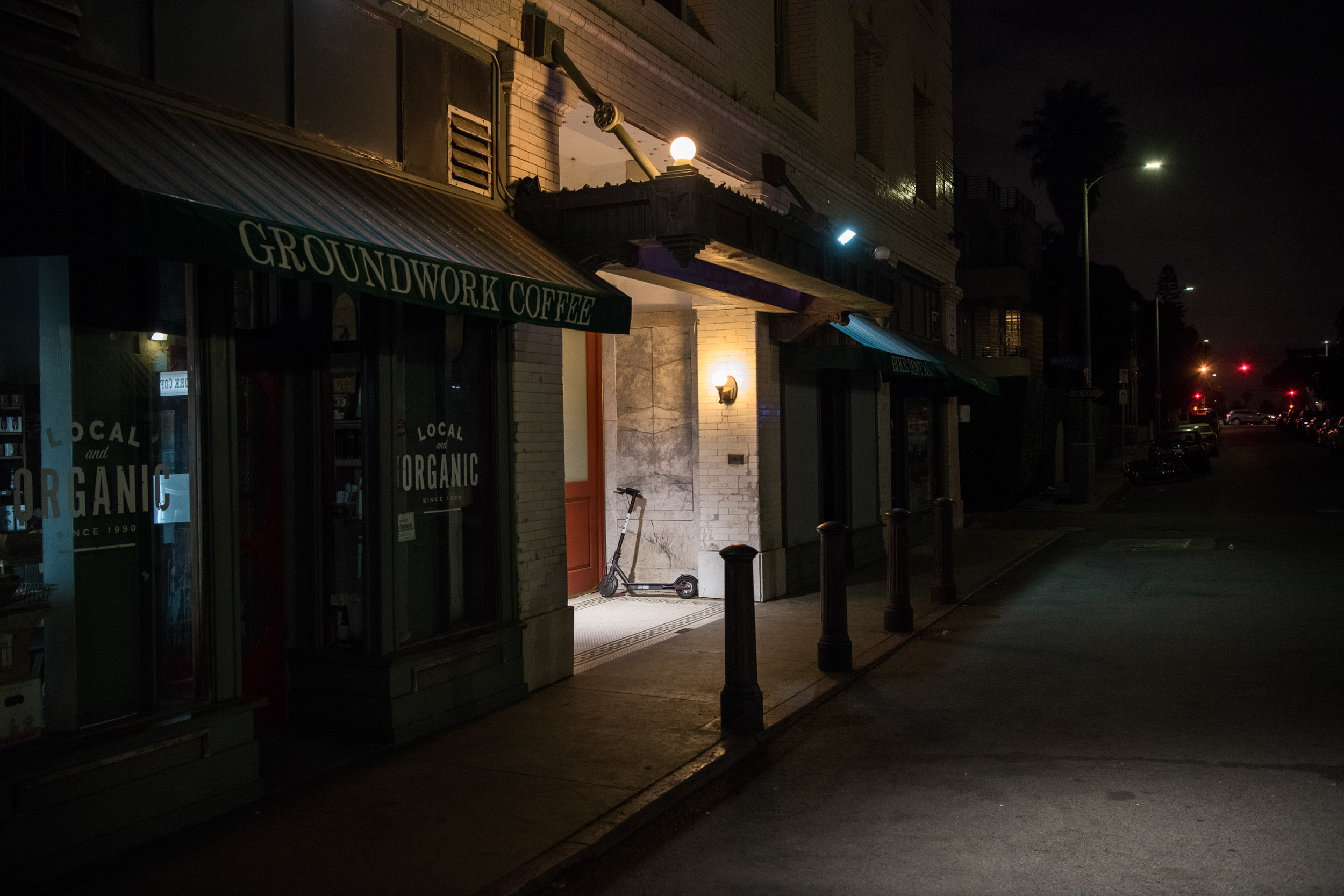 A bird scooter beneath a street lamp at night in Venice Beach.