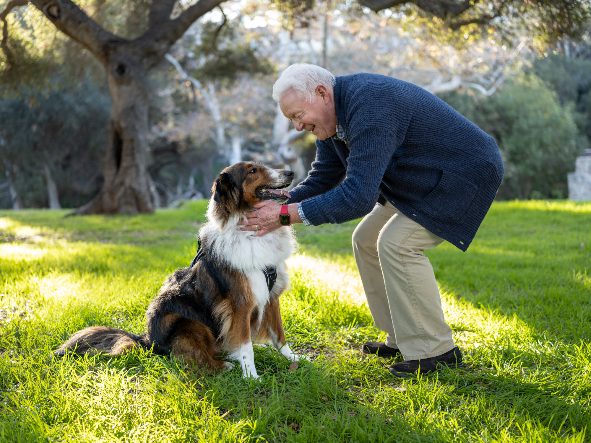 An older man bends down to pet his dog for a tech lifestyle advertisement in Santa Barbara, Calif.