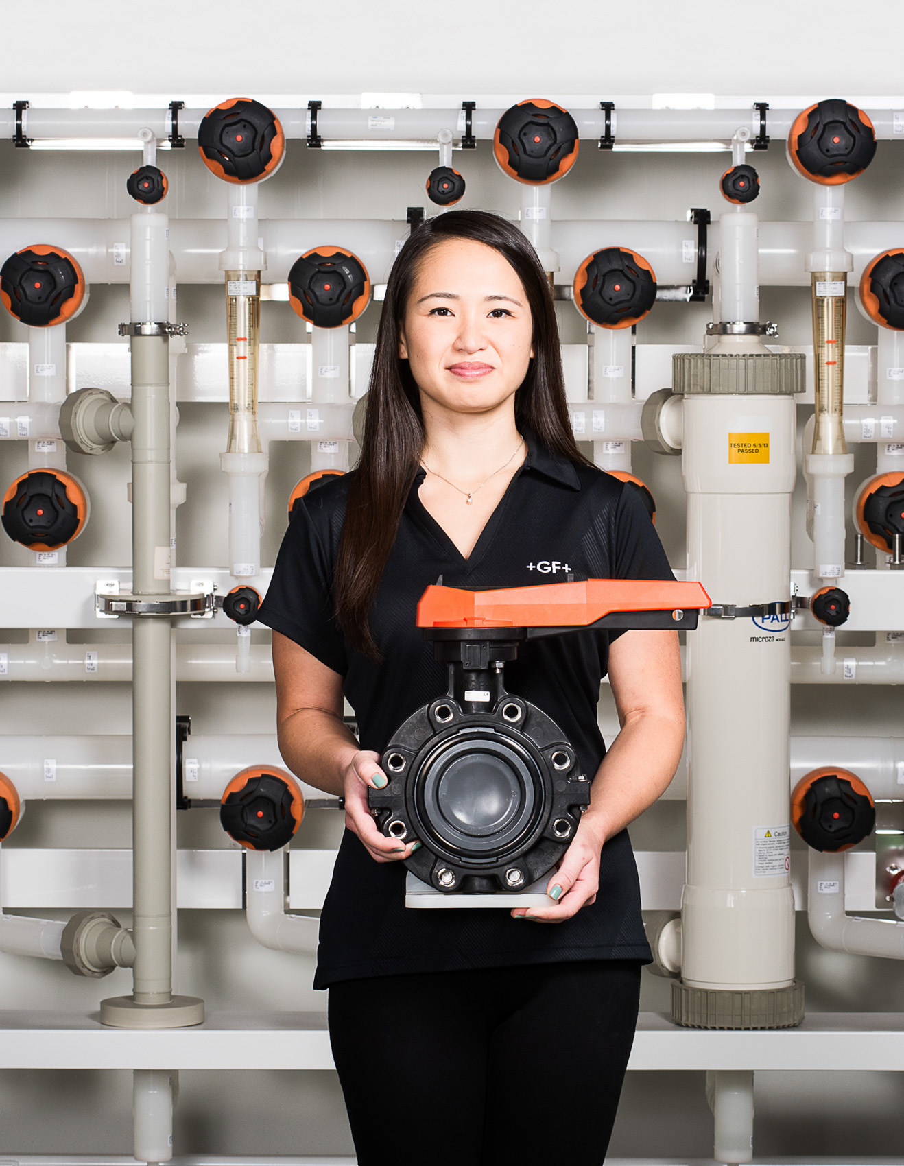 Portrait of female employee holding pipe valve at George Fischer in Irvine, Calif.