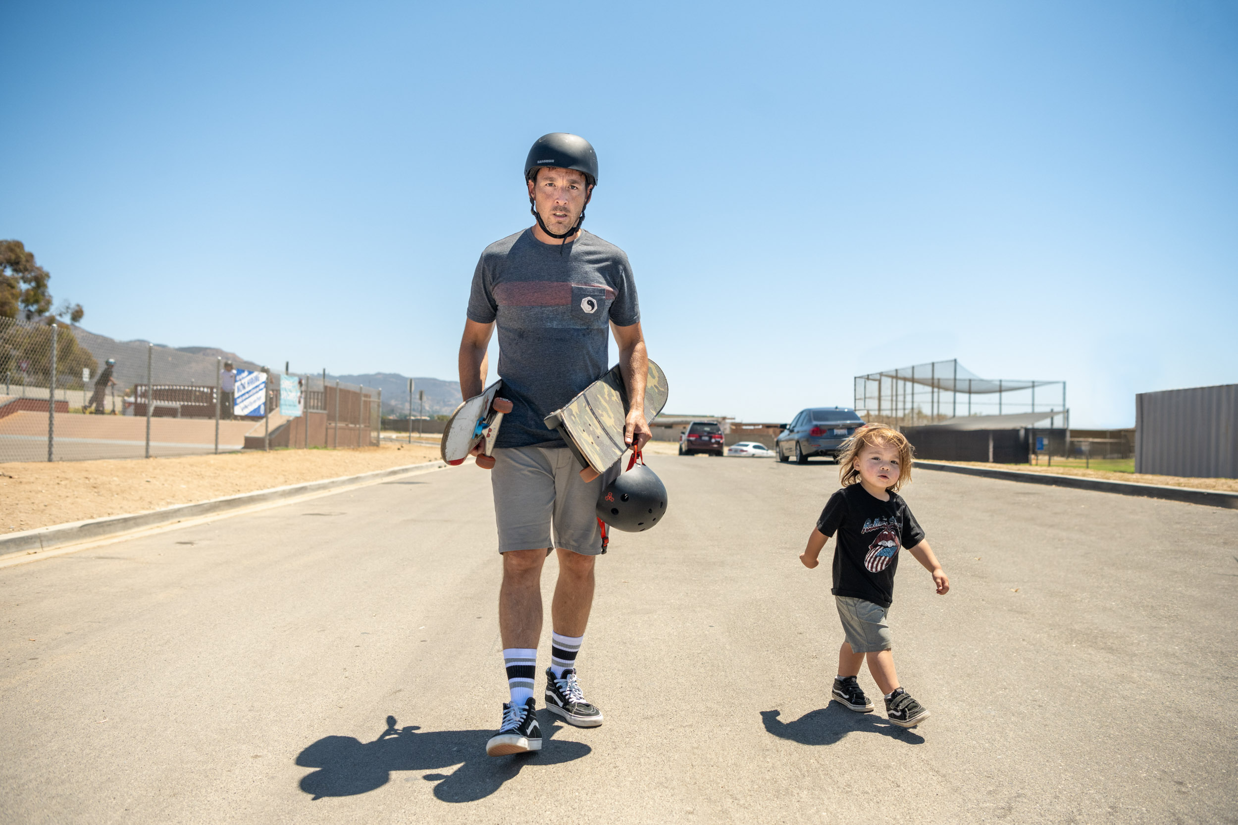 A father and son walk with skateboards in Malibu