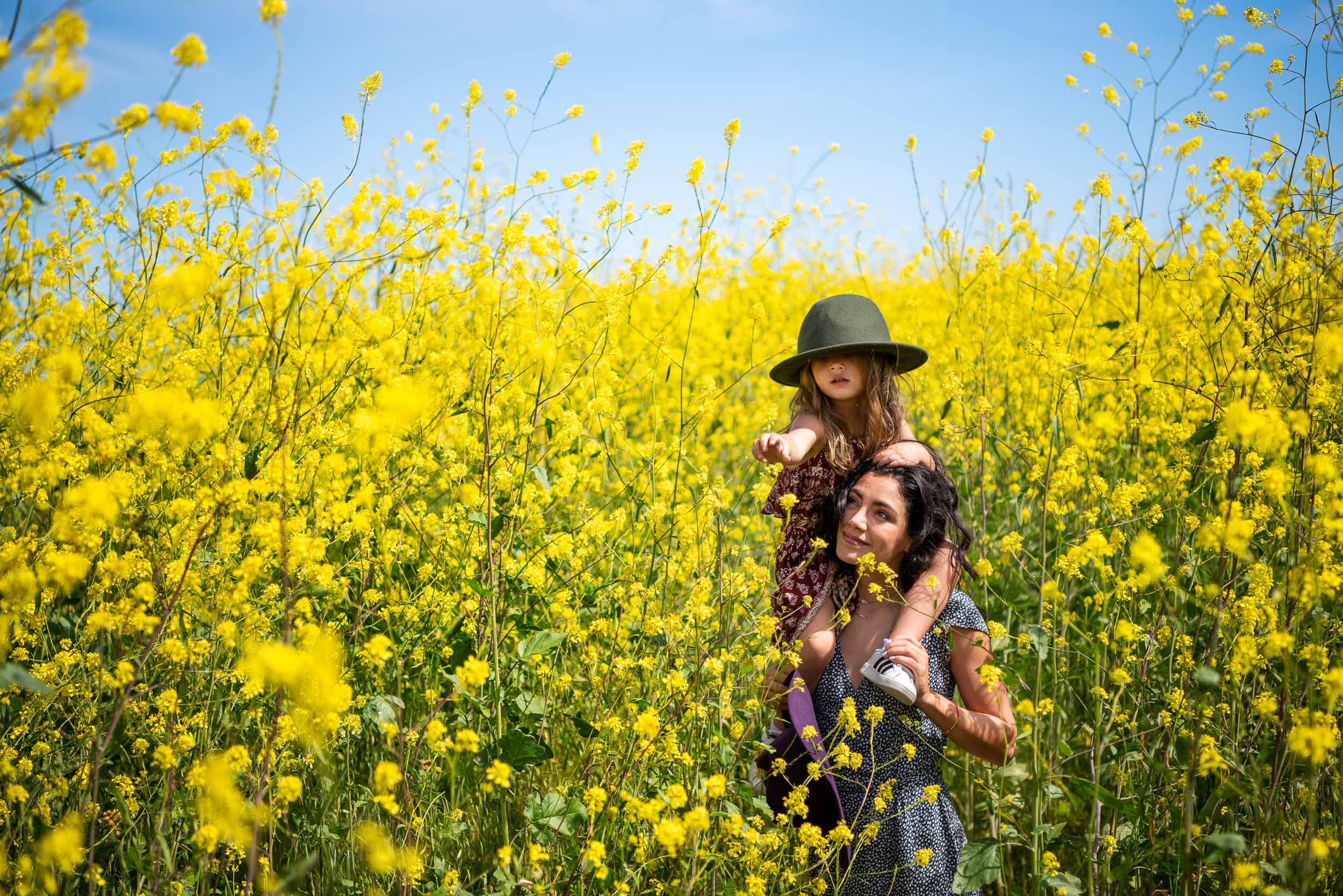 A mother holds her daughter on her shoulders in a field of wildflowers during a superbloom in Malibu, Los Angeles.
