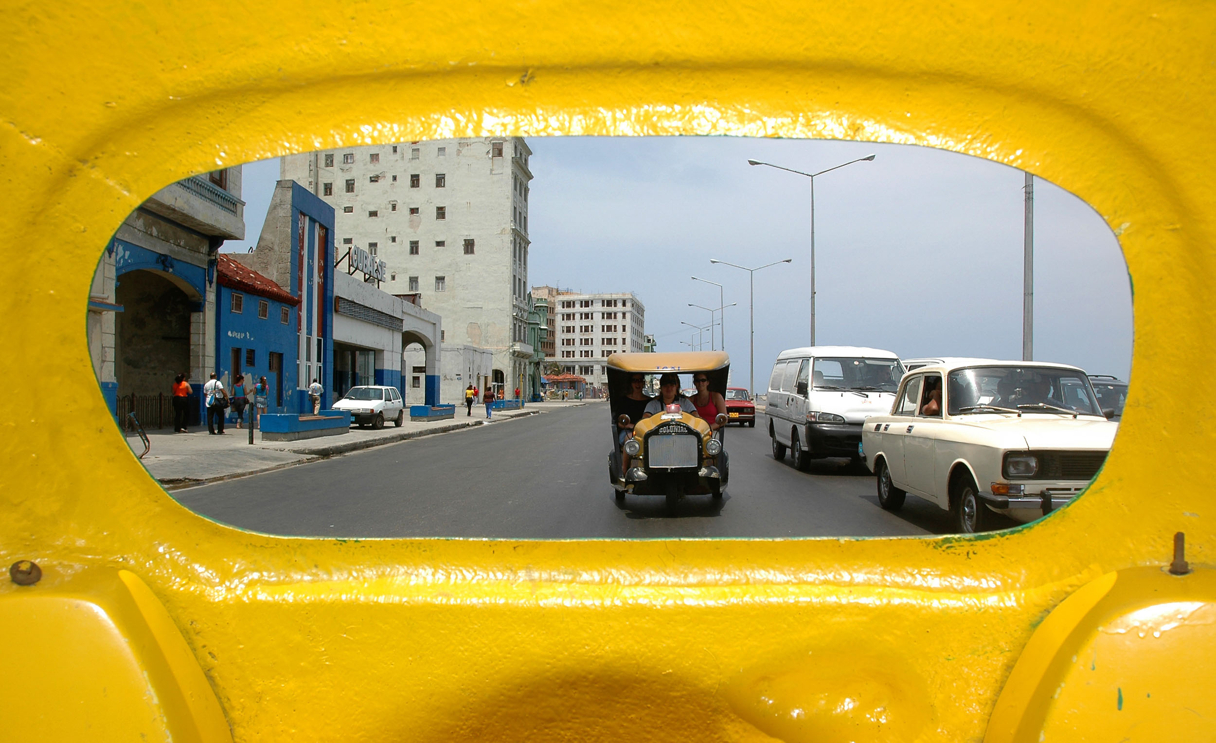 A cab is framed through a yellow taxi window on El Malecon in Havana, Cuba.