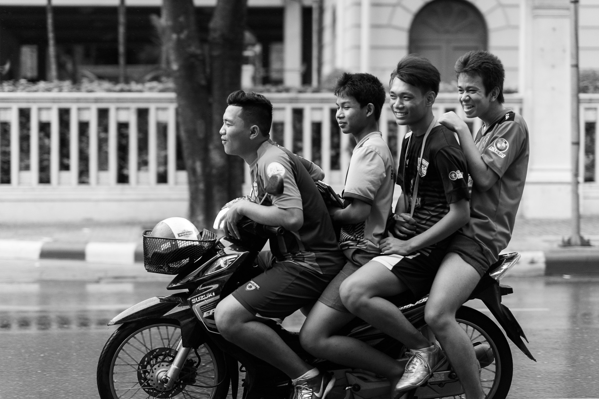 A group of several boys ride a moped in the rain in Thailand.