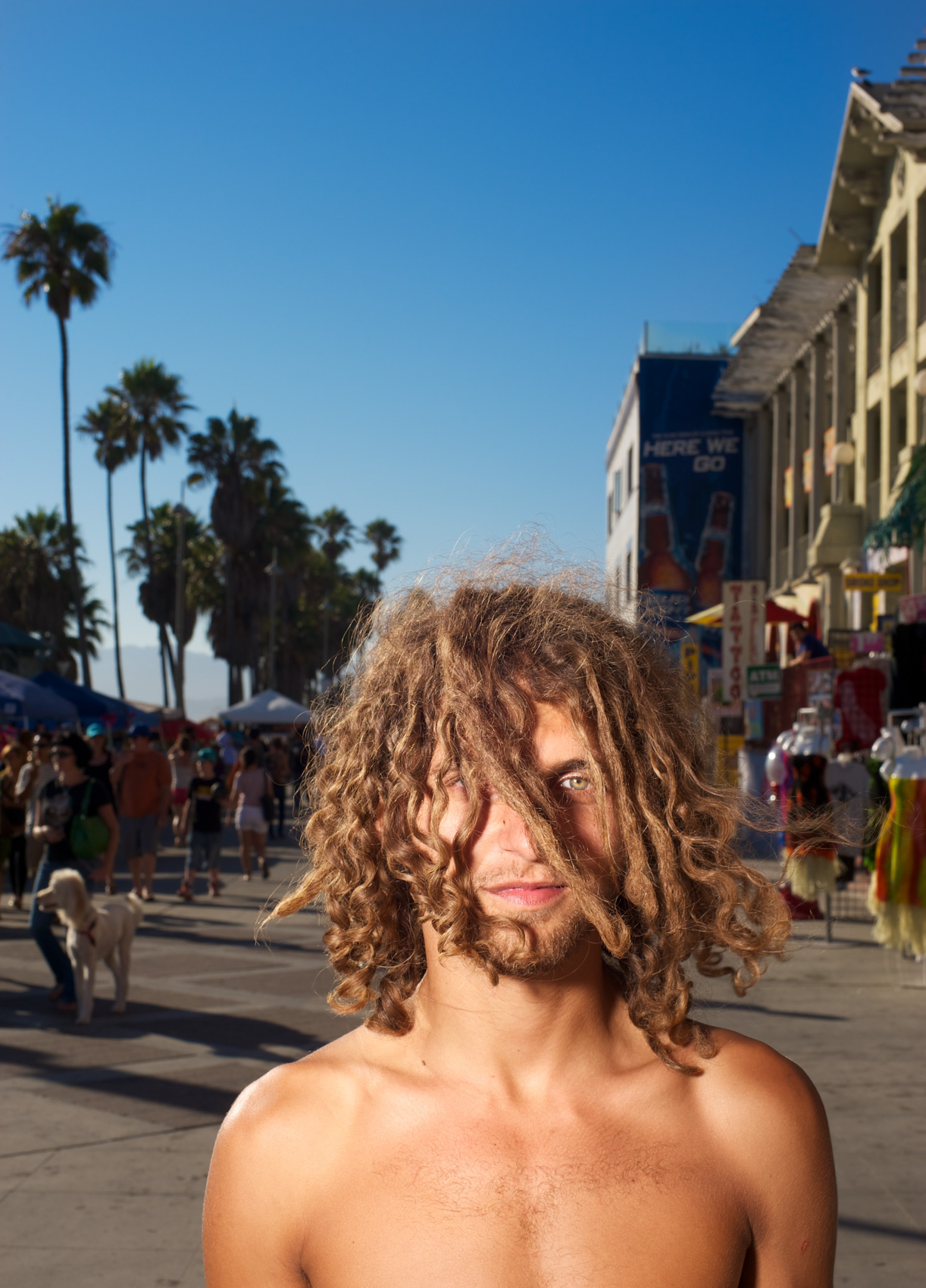 Portrait of a young man framed through curly hair on the Venice Beach boardwalk.