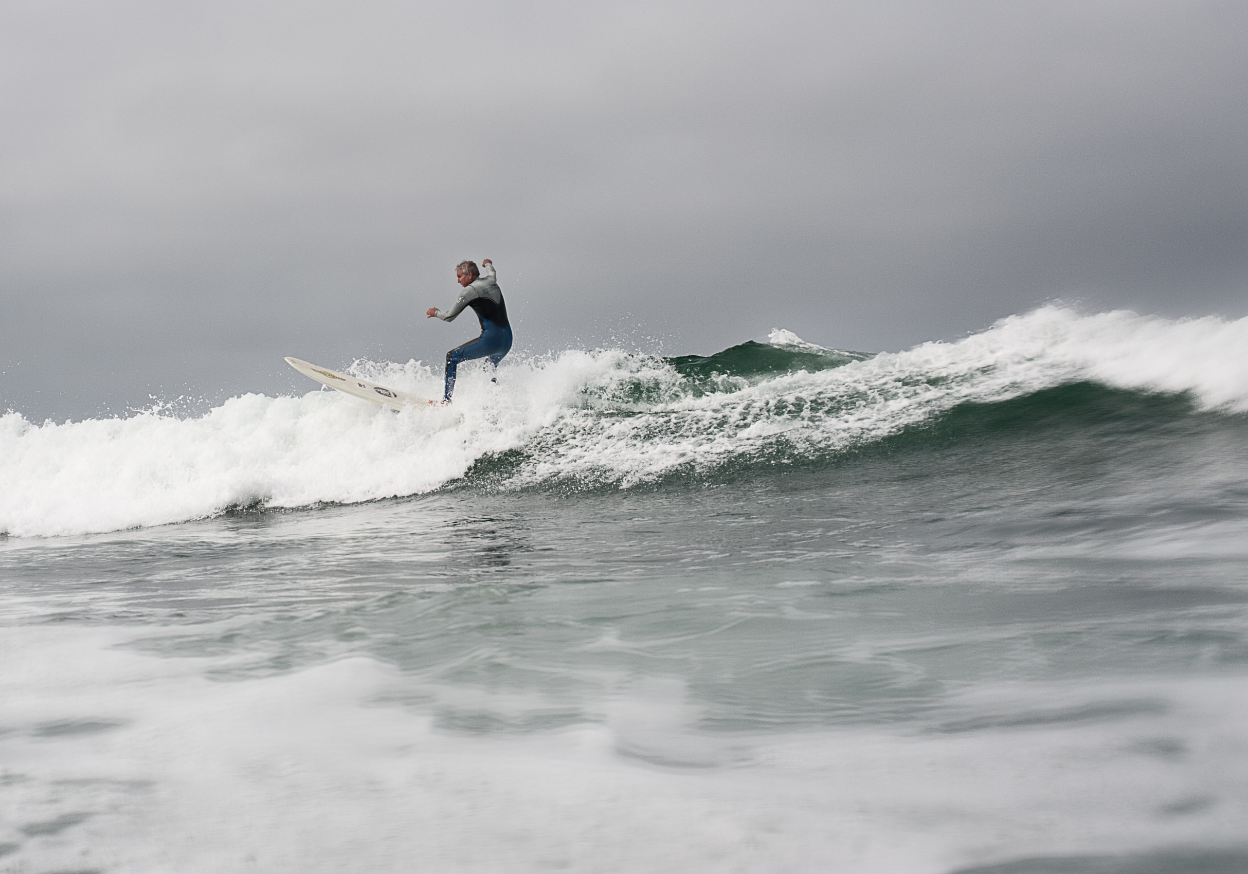 An older surfer catches a wave in choppy waters at San Onofre State Beach, California.