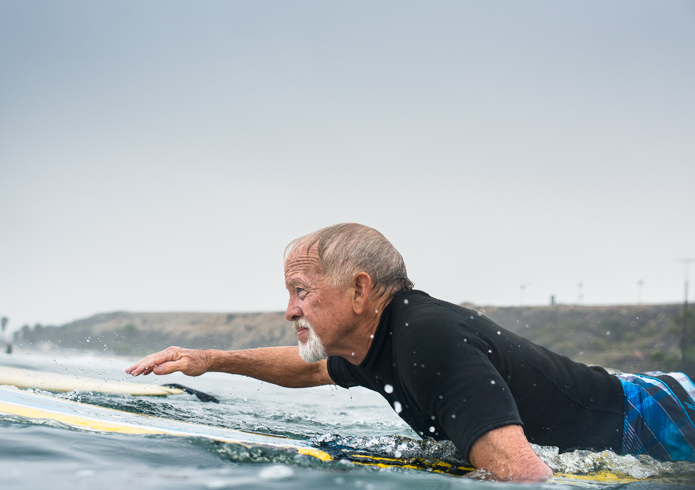 A senior surfer paddles out at San Onofre State Beach, San Clemente, Calif.