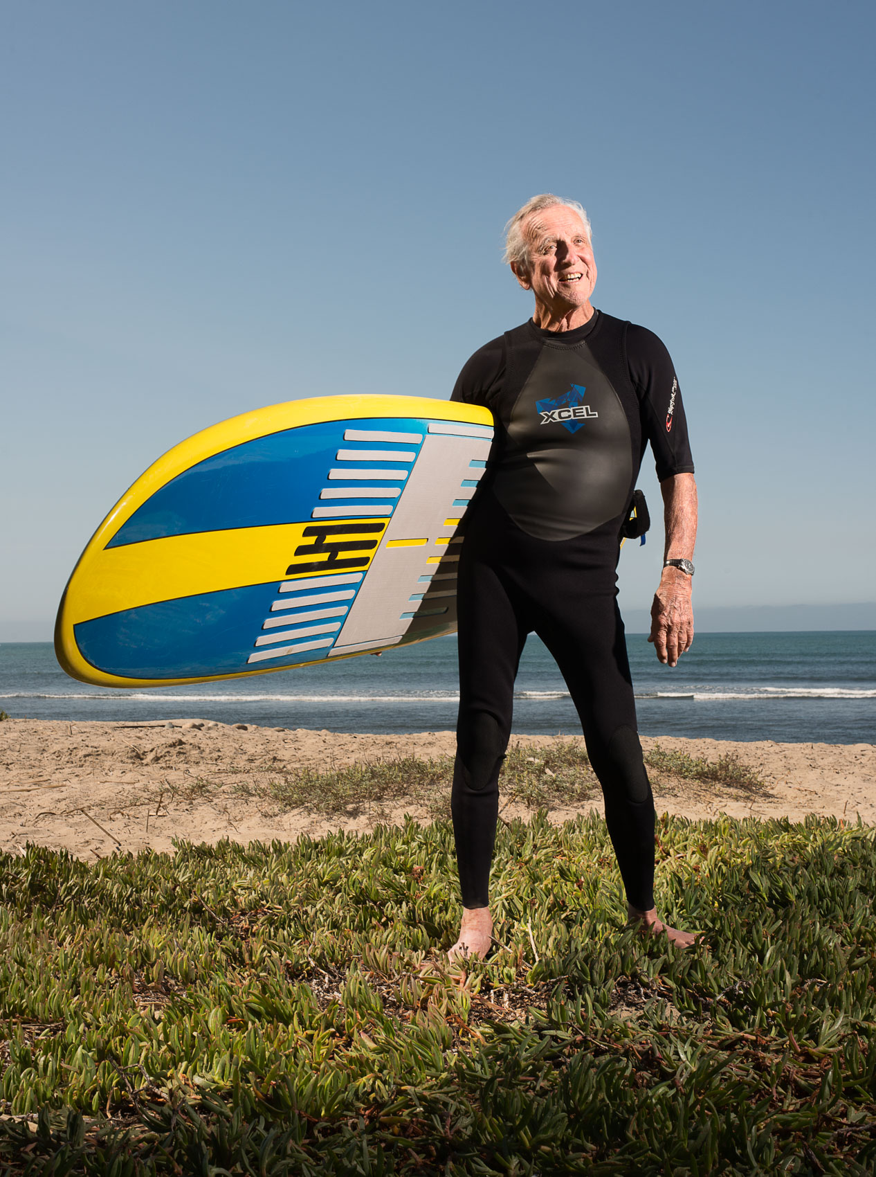 Senior surfer Frank Trane portrait with board at San Onofre State Beach.